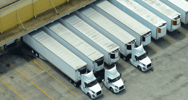 Big corporate shipment center with many cargo semi trucks unloading and uploading retail products for further retail shipment. Global market concept.