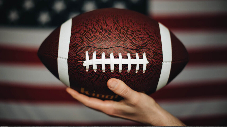person holding football close up