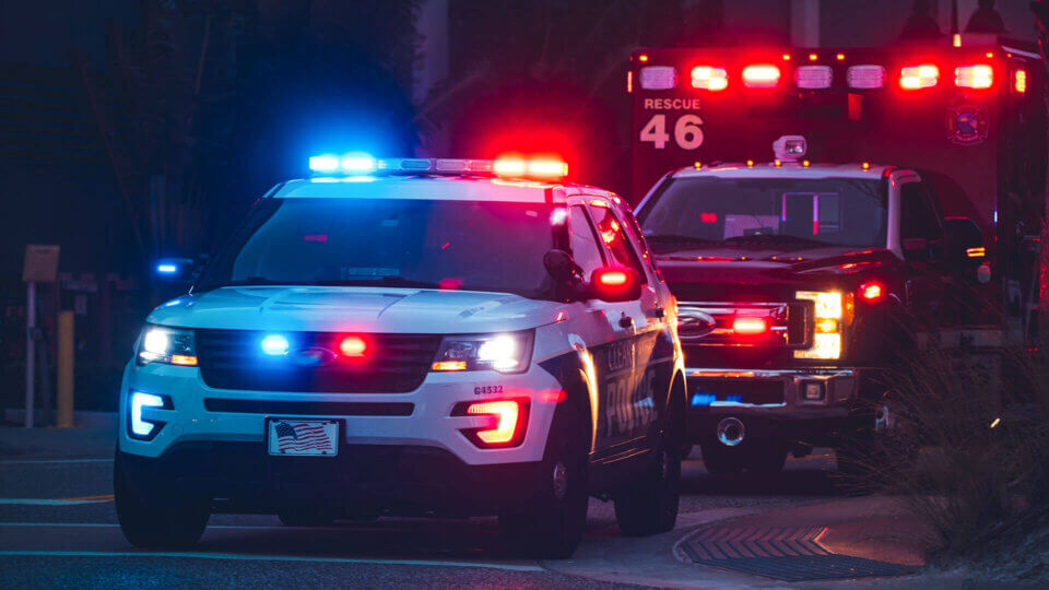 Police SUV with lights on escorting an Ambulance with lights on