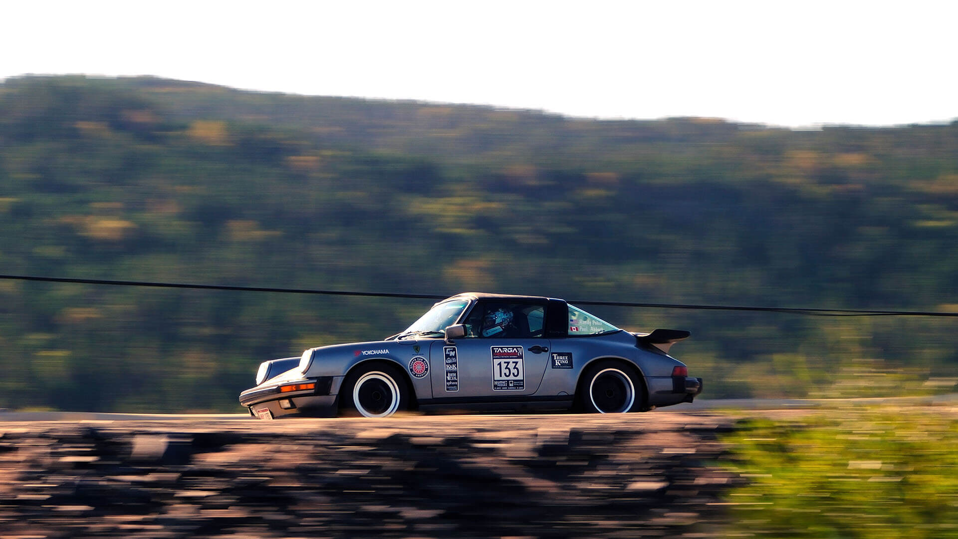 Targa competitor driving a Porsche fast as the background flies by