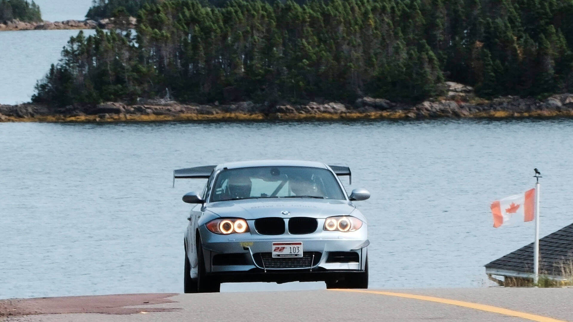 BMW racing towards the viewer with a view of a lake behind them